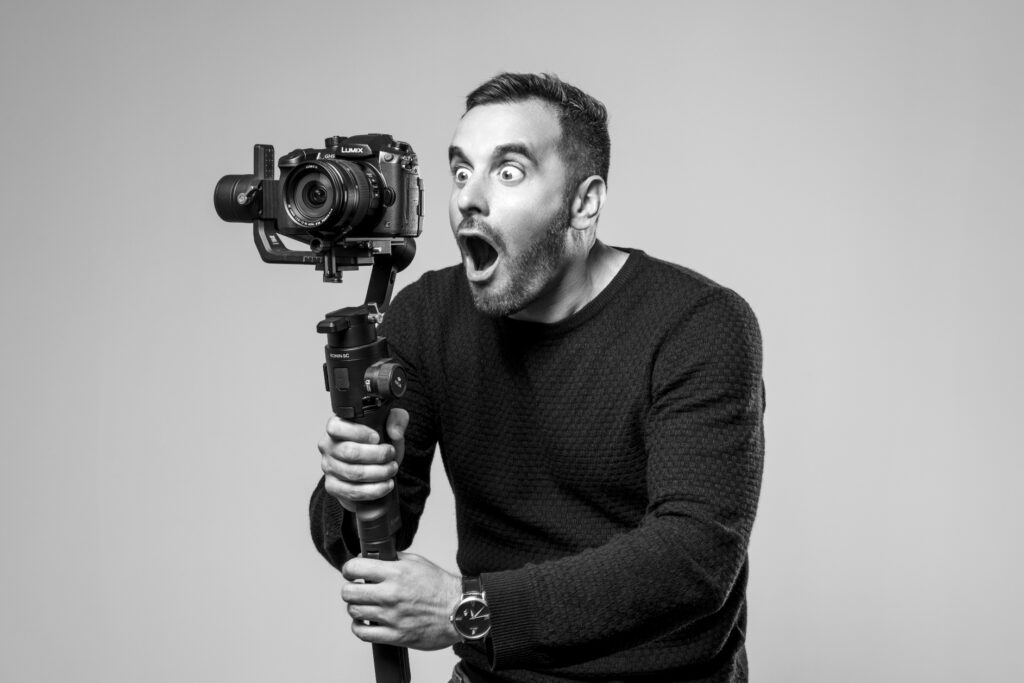 Julien Soudant, vidéaste, prend une expression surprise avec sa caméra sur stabilisateur